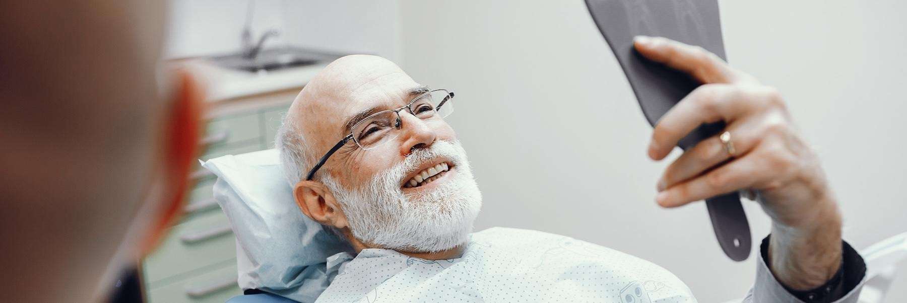 A bearded man sits in a dentist chair, considering All-on-4® implants.