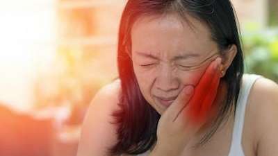 Woman holding face in pain from dental emergency in Foothill Ranch, CA