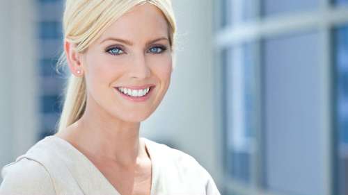 A woman smiling confidently, showcasing her straight teeth after completing Invisalign® treatment