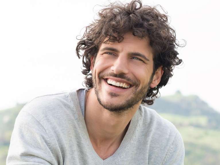 Smiling man outdoors showing confidence after treatment for those struggling with loose partial dent