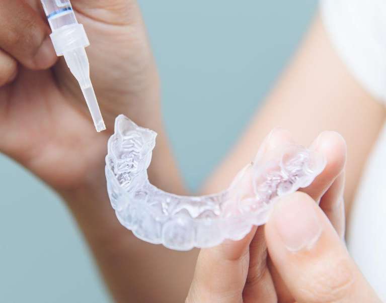 A hand grips a clear plastic toothbrush, representing essential tools for achieving a brighter smile