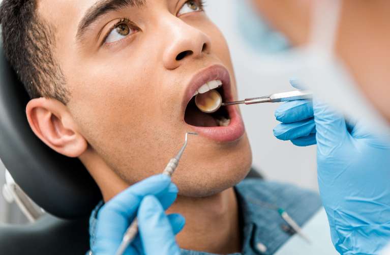 A dentist checks a man's teeth, capturing the tension of a dental emergency situation in the clinic.